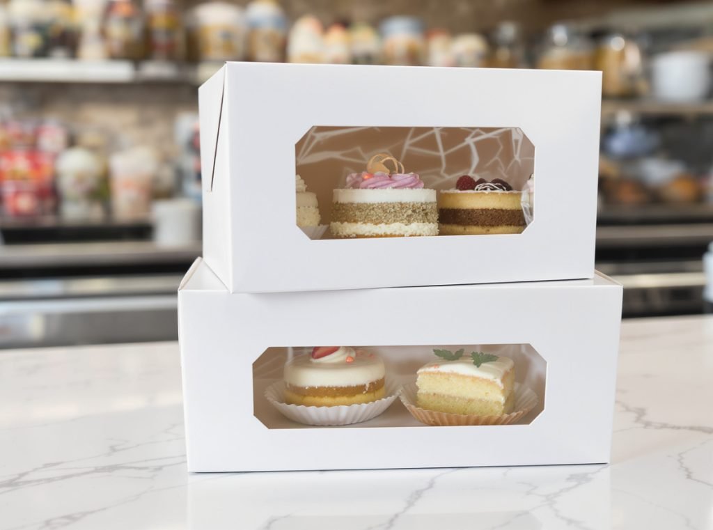 Food-grade paperboard bakery boxes with decorated cakes and pastries